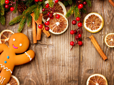 holiday background with fir tree sprigs, red berries, dried orange slices, and a gingerbread man