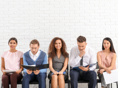 five people seated in a row waiting for a job interview