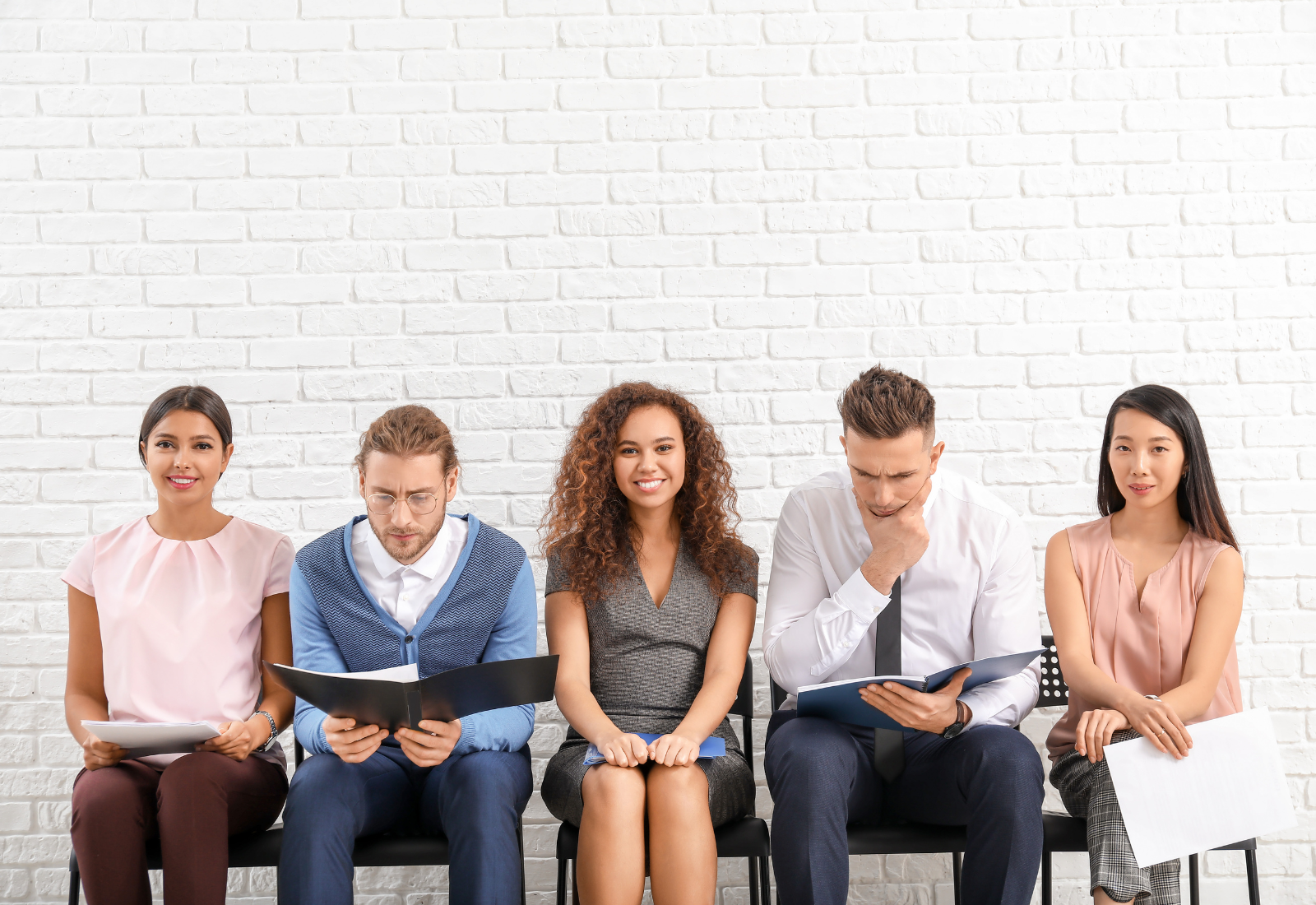 five people seated in a row waiting for a job interview